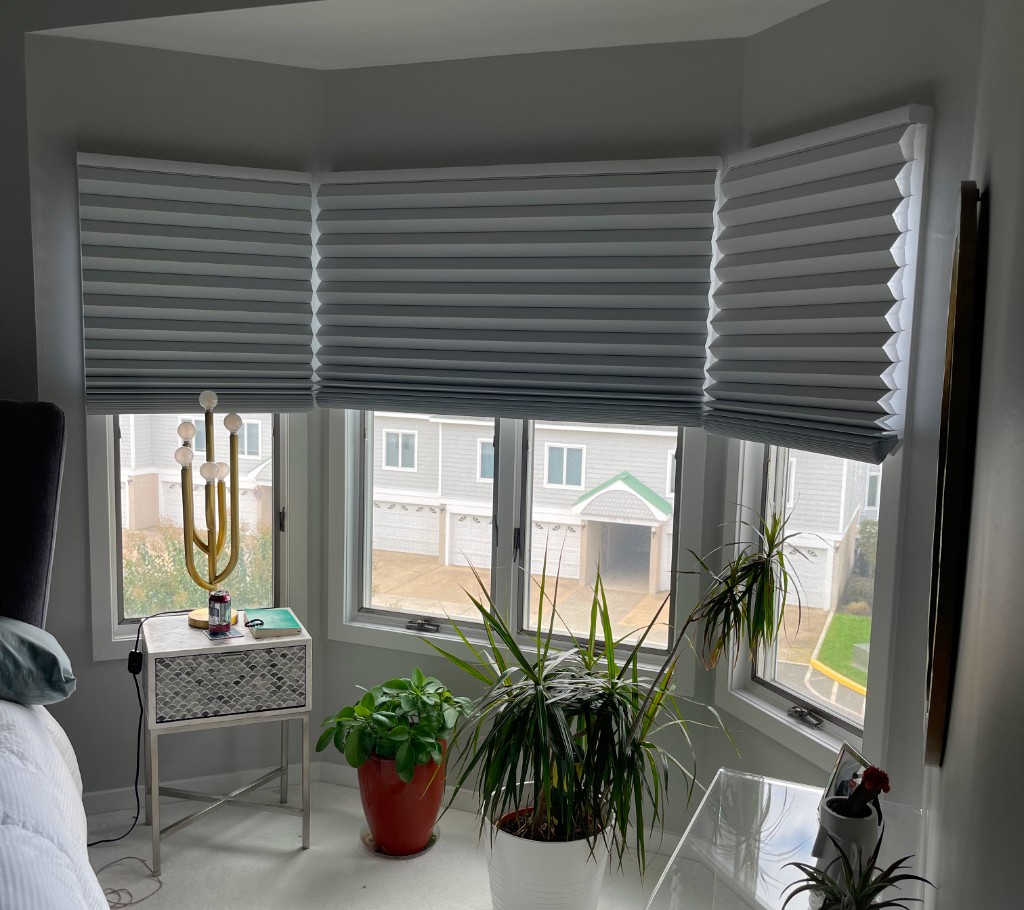 Custom cellular shades on a three-part bay window in a bright, modern bedroom with soft natural light